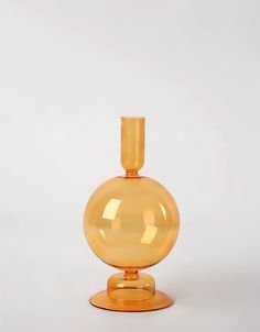 a yellow glass vase sitting on top of a table next to a white wall and floor