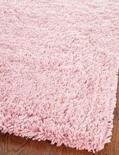 a pink rug on top of a wooden floor with a wood floor in the background