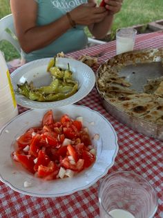 a woman sitting at a table with plates and bowls of food on top of it