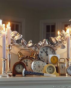 several clocks are sitting on a mantle with candles