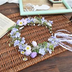 a wicker basket with flowers and ribbon around it on top of a wooden table