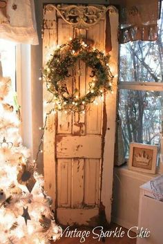 an old door is decorated with wreaths and lights for the christmas tree in front of it