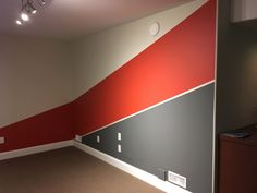 an empty room with red, grey and white stripes painted on the wall