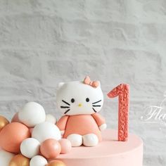 a pink hello kitty cake with gold and white decorations