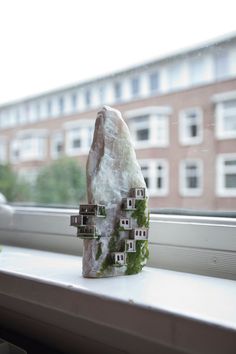 a house made out of rocks sitting on top of a window sill in front of a building