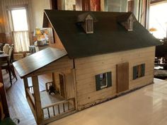 a doll house made out of wood with windows and doors on the roof, sitting on a table in a living room