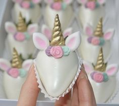 a hand holding a heart shaped cake with unicorns on it and flowers in the middle