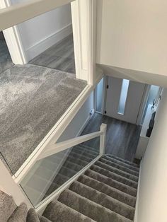 a staircase with glass railing and grey carpet