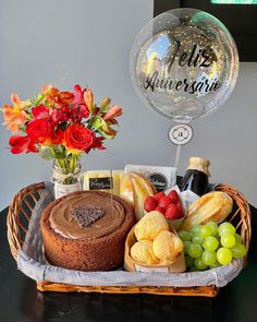 a basket filled with cake, bread and fruit next to a balloon that says puliz anniversary