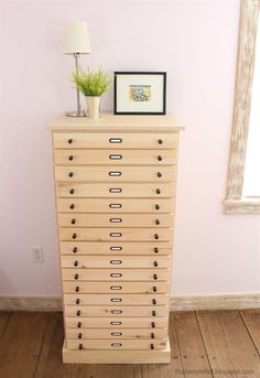 a wooden dresser with drawers and pictures on top in a pink room next to a window