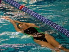 a woman swimming in a pool wearing a green and black swim suit