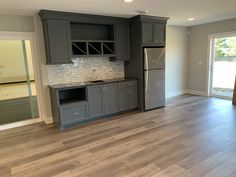 an empty kitchen with gray cabinets and wood flooring in the middle is seen from across the room