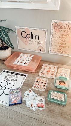 a wooden table topped with lots of cards and magnets next to a potted plant