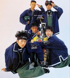 a group of young men standing next to each other in front of a white wall