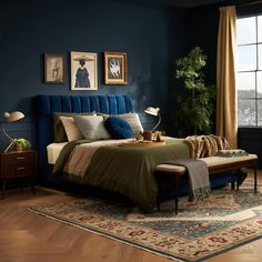 a bed room with a neatly made bed next to a large window and a rug on the floor