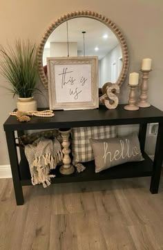 a black console table with pillows and a mirror