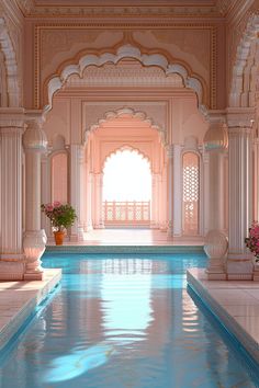 an indoor swimming pool with blue water and white pillars, surrounded by pink flowers on either side