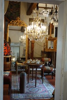 a dining room with a chandelier and table in the middle, surrounded by antique furniture