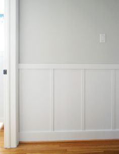 an empty room with white paneling and wood floors