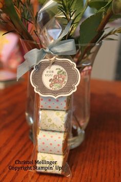 a glass vase filled with flowers on top of a wooden table next to a sign