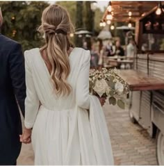 a bride and groom walking down the street holding hands