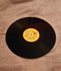 an old black record with yellow and orange labels on it sitting on a white sheet