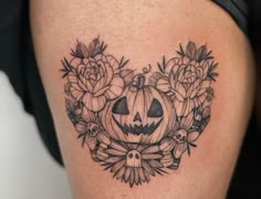 a black and white photo of a pumpkin with flowers around it's face on the thigh