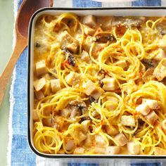 a casserole dish with chicken, noodles and cheese on a blue checkered cloth