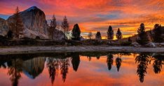 an image of a beautiful sunset with mountains in the background and trees reflected in the water