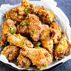 a bowl filled with fried food sitting on top of a black table next to a white napkin