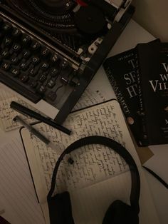 an old typewriter, headphones and notebooks on a desk with writing paper