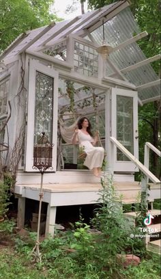 a woman in white dress standing on the porch of a house