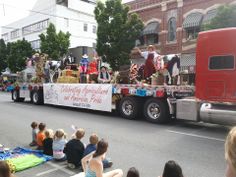 a parade float with people sitting on the ground