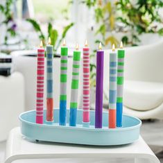 there are seven candles that have been placed in a tray with different colors on them