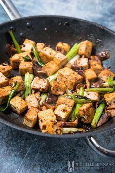 tofu and asparagus stir fry in a wok on a blue surface