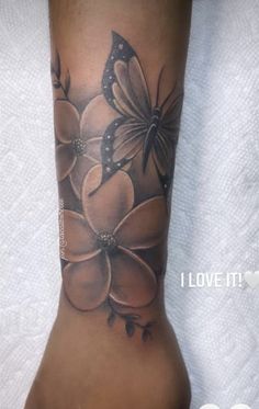 a woman's foot with flowers and butterflies on the bottom part of her leg