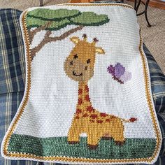 a crocheted baby blanket with a giraffe on it and a bird in the background