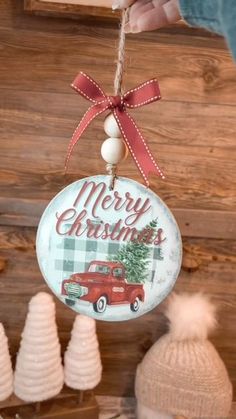 a christmas ornament hanging from a string with a red truck and trees on it