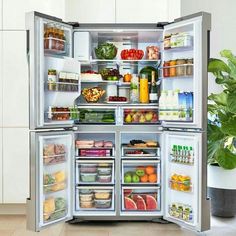 an open refrigerator filled with lots of different types of food and drinks, sitting on the floor next to a potted plant