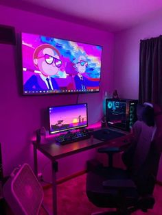 a computer desk with two monitors and a keyboard in front of a large television screen