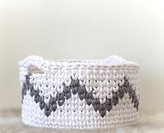 a white and black basket sitting on top of a fur covered floor