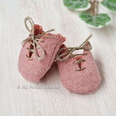 two pink baby shoes are sitting on a table next to some green leafy plants