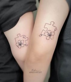 two matching tattoos on the legs of people with puzzle pieces and flowers in their hands