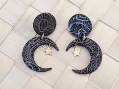 the earrings are made from wood and decorated with black and white designs, stars and crescents