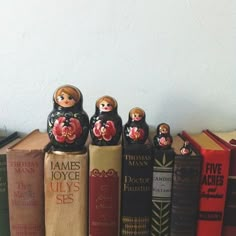 a row of books sitting on top of each other in front of a white wall