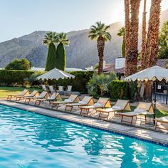 an outdoor swimming pool with lounge chairs and umbrellas