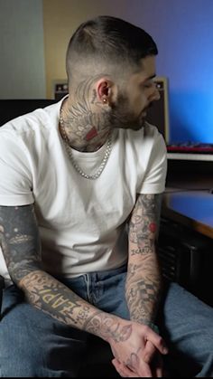 a man with tattoos sitting in front of a computer