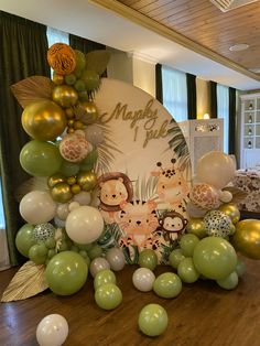 a table topped with lots of balloons and jungle animals on top of it's head