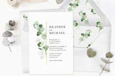 the wedding stationery is laid out with greenery