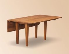 a small wooden table with two legs and a drawer on the top, against a beige background